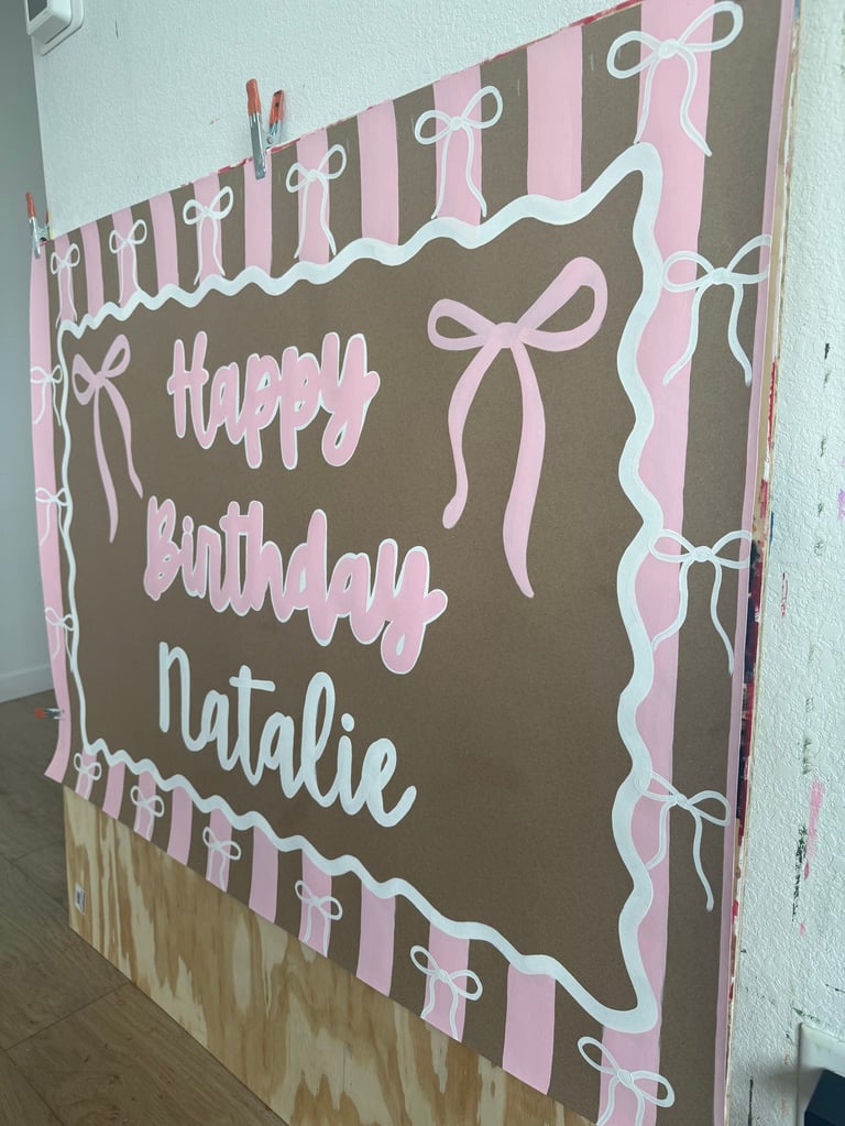 Handmade birthday poster with pink bows and striped borders on brown background saying Happy Birthday Natalie