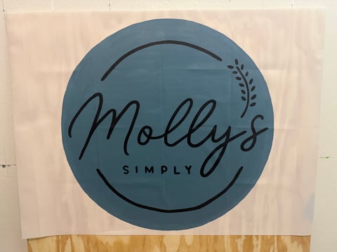 Mollys Simply logo featuring blue circular design with cursive text and decorative leaf element