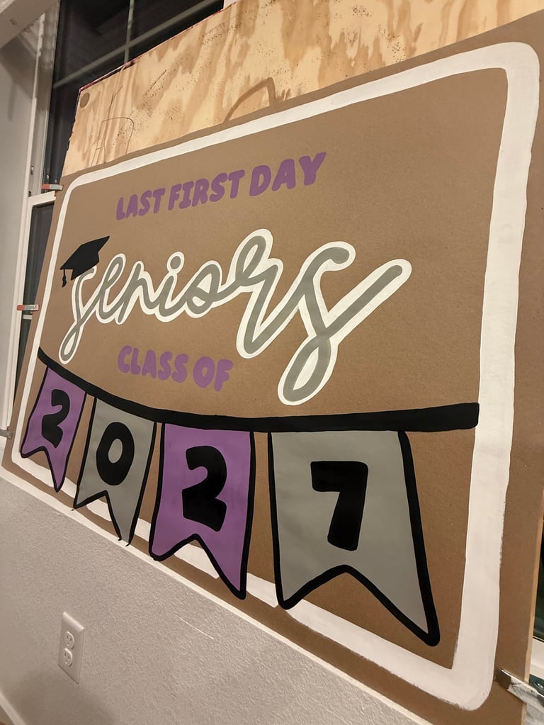 Cardboard sign reading Last First Day This Is Class Of 2037 in purple and white text with banner pennants showing 2037