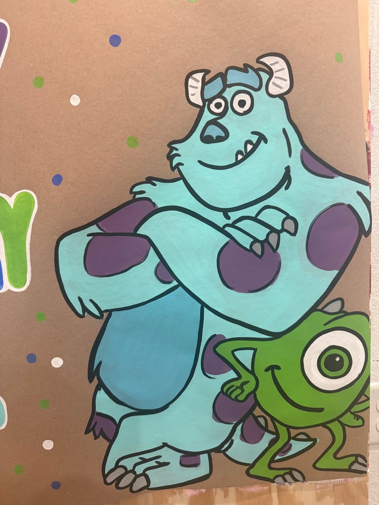 Cartoon illustration of a blue furry monster with horns hugging a small green creature on a tan background with colorful dots