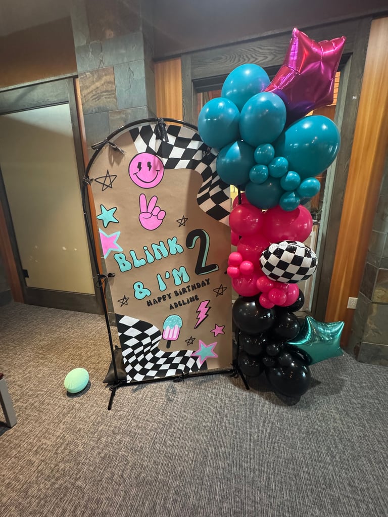 Blink-182 birthday party display with decorated arch, colorful balloons, and checkered pattern elements in a room