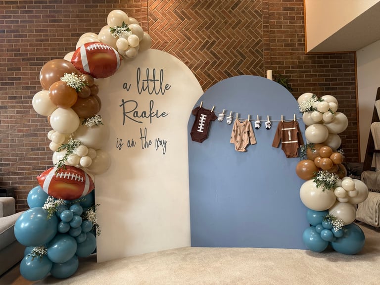 Decorative arch display with a little leafie football theme, featuring balloons, footballs, and fall decorations in cream and blue