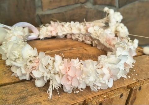 Floral crown wreath with white and pale pink hydrangeas and babys breath on wooden surface