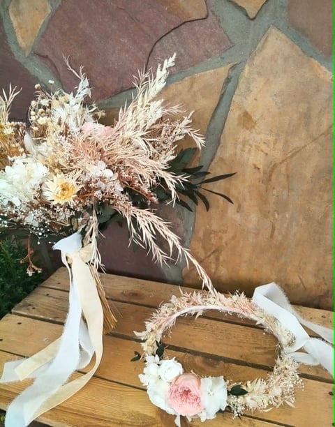 Wedding bouquet and wreath with dried pampas grass, white flowers, and pink accents on wooden surface