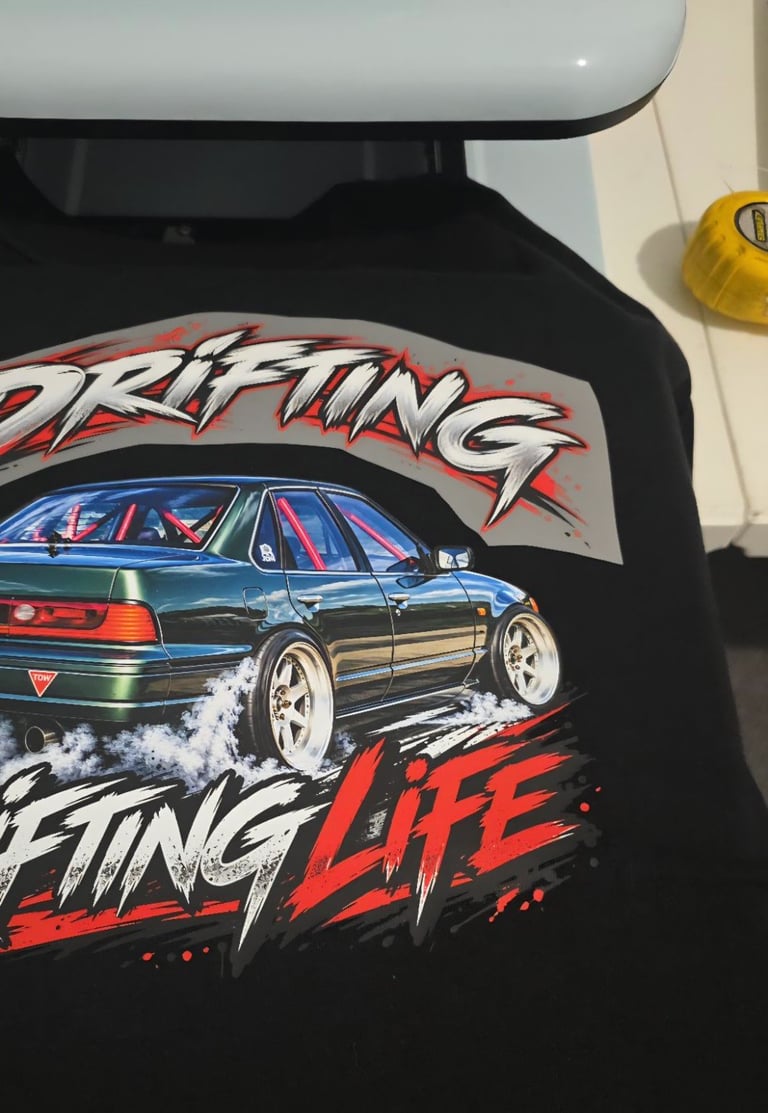 Black t-shirt with drifting car graphic featuring a blue sedan with smoke and red Drifting Life text