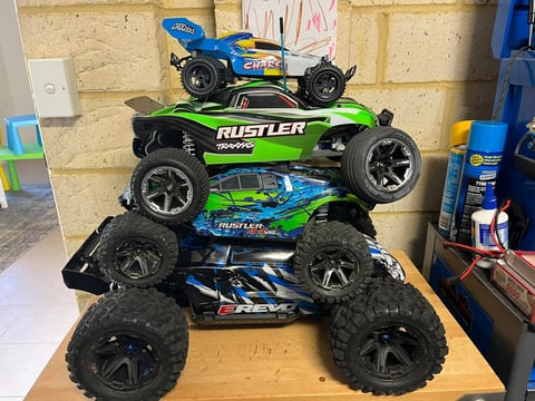Stack of five toy RC remote control trucks displayed on a wooden table