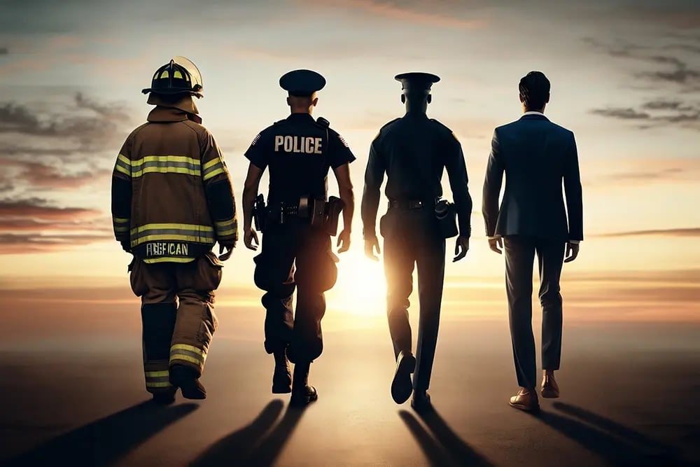 Four uniformed emergency responders - firefighter, police officer, and two other officials - walking together against a sunset sky