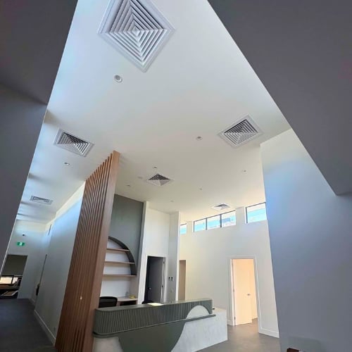 Modern white interior hallway with wooden accent wall, ceiling vents, and multiple doorways leading to different rooms