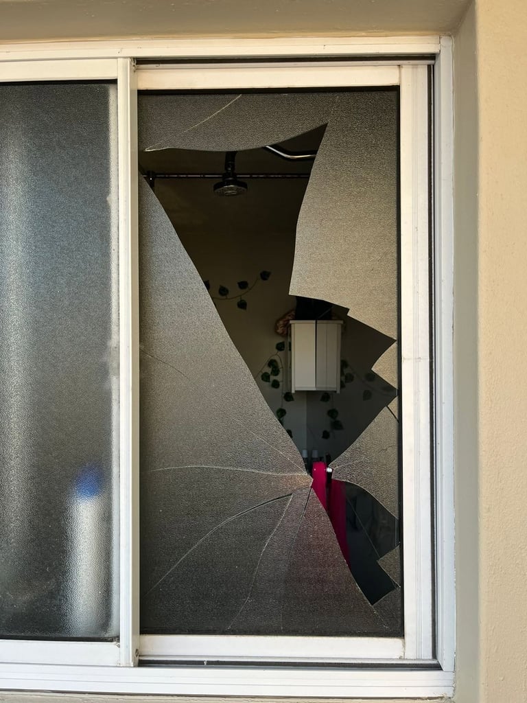 Broken glass door with shattered pane featuring black and red shards in a geometric pattern.
