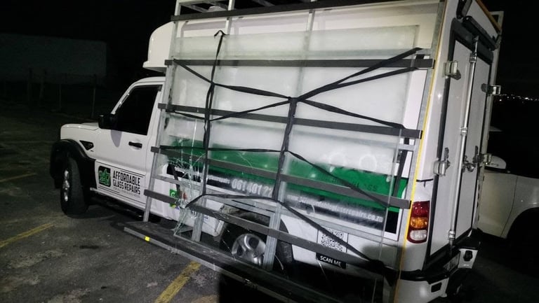 247 Affordable Glass Repairs mobile workshop van photographed from behind at night in a Vredehoek parking lot, with the side door open, glass racks and strapping visible inside the cargo box, and the company branding — Affordable Glass Repairs, 061 401 22..., affordableglassrepairs.co.za — clearly shown on the side.