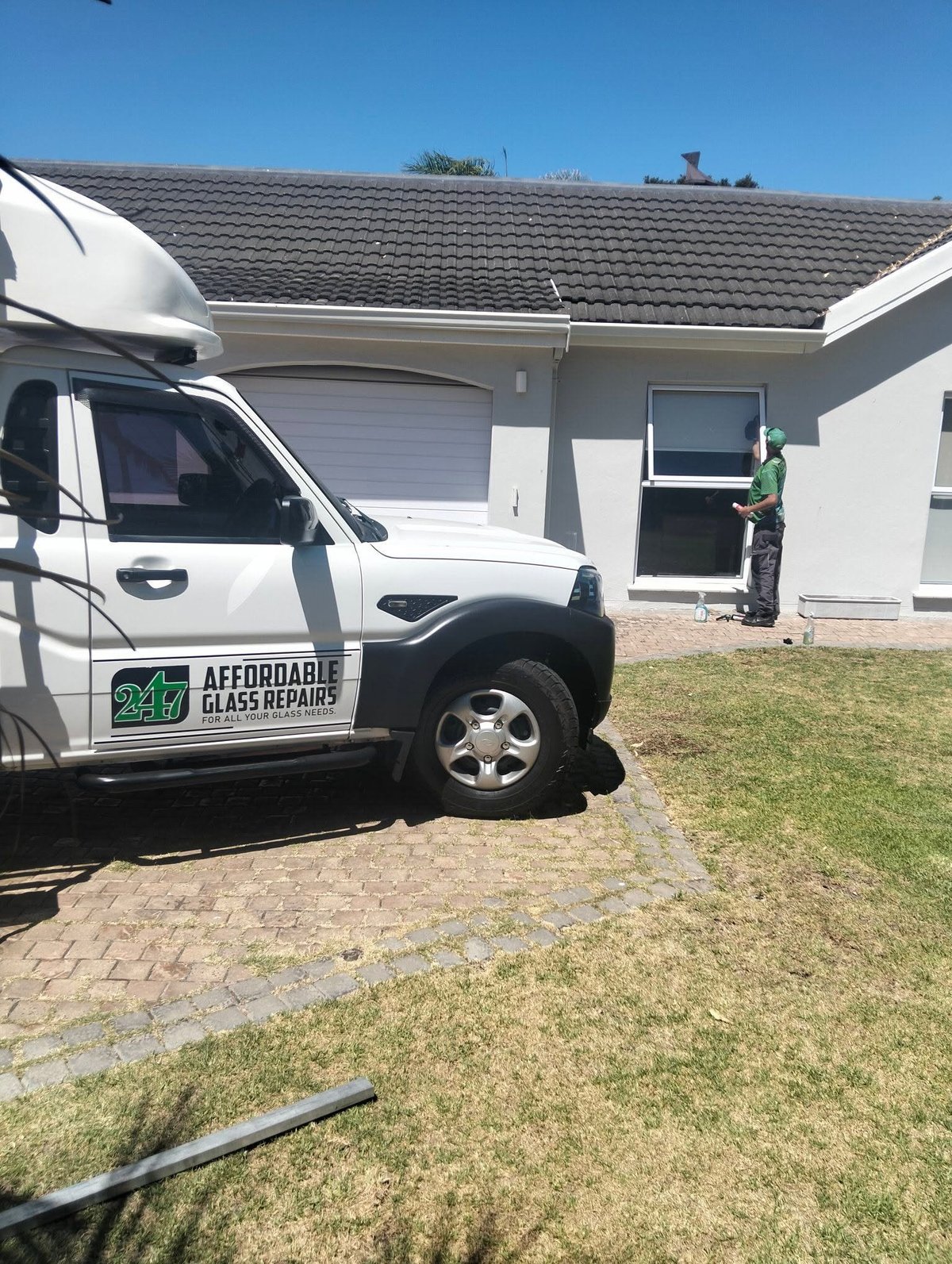Affordable Glass Repairs service van parked outside a white house with a technician visible near the entrance