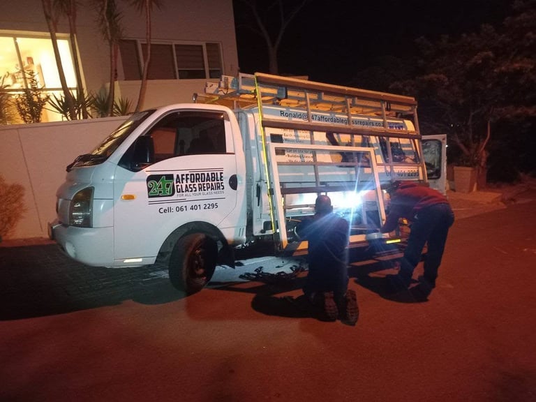 White delivery truck with metal cargo rack parked at night with two workers standing beside it