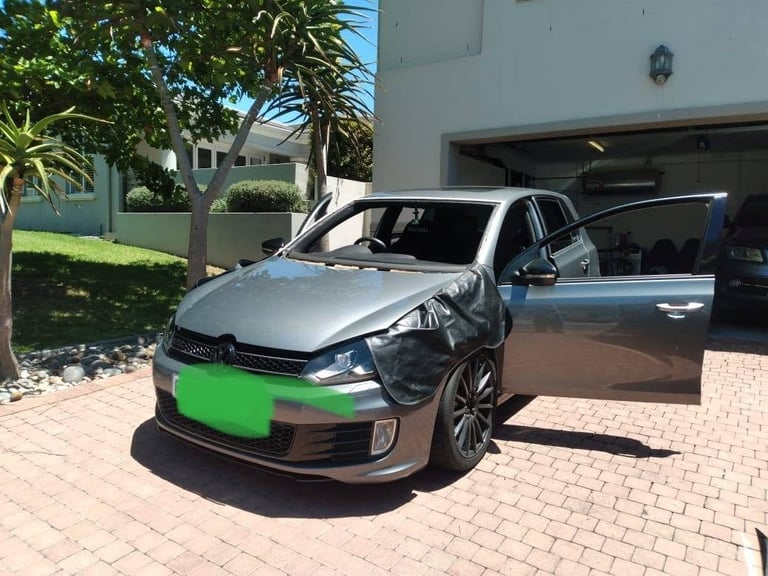Silver vehicle in the driveway of a Durbanville home with its windscreen covered in protective film and taped over, ready for the 247 Affordable Glass Repairs mobile team to carry out the windscreen replacement on site.