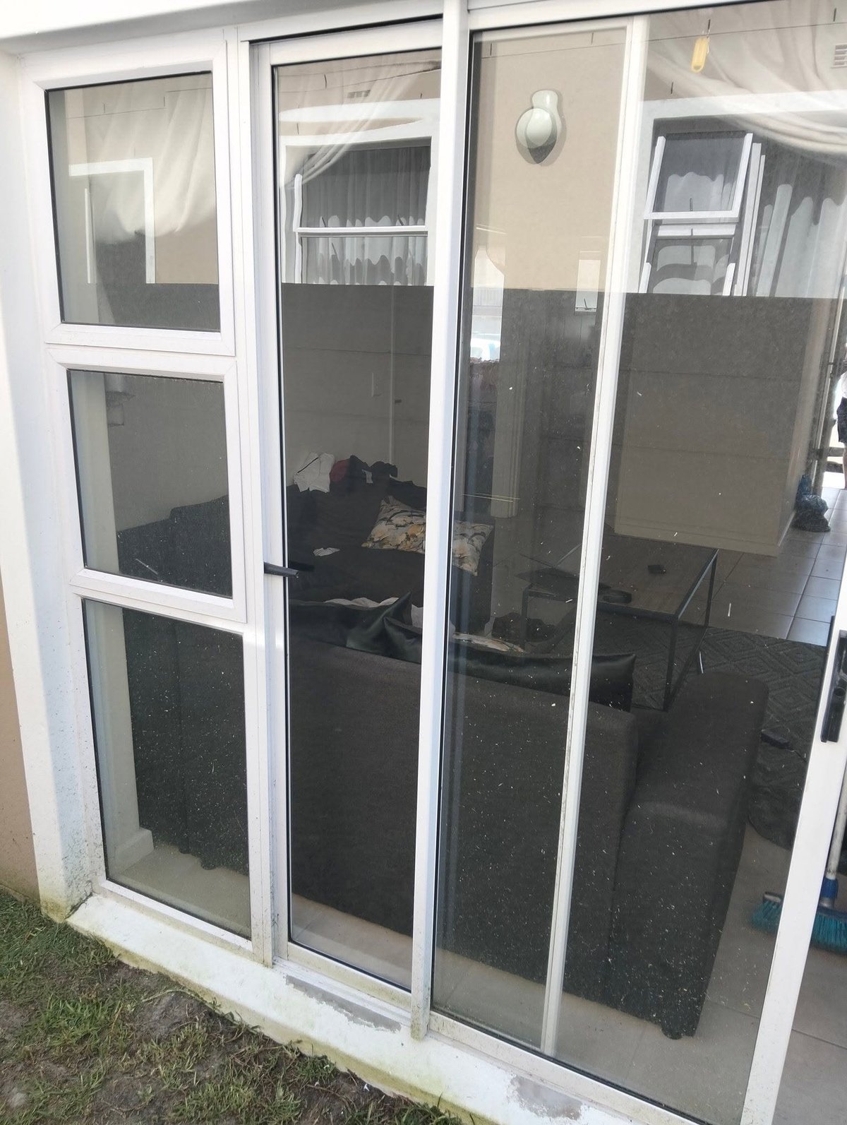 Newly installed white-framed sliding glass patio doors with dark tinted lower panels and clear upper panels, viewed from outside a residential home