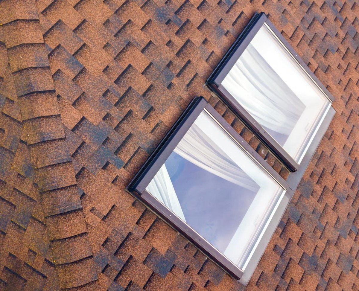 Two rectangular skylights installed on a brown asphalt shingle roof, viewed from above.
