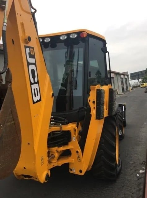 Yellow excavator with open cab door showing interior controls on industrial lot