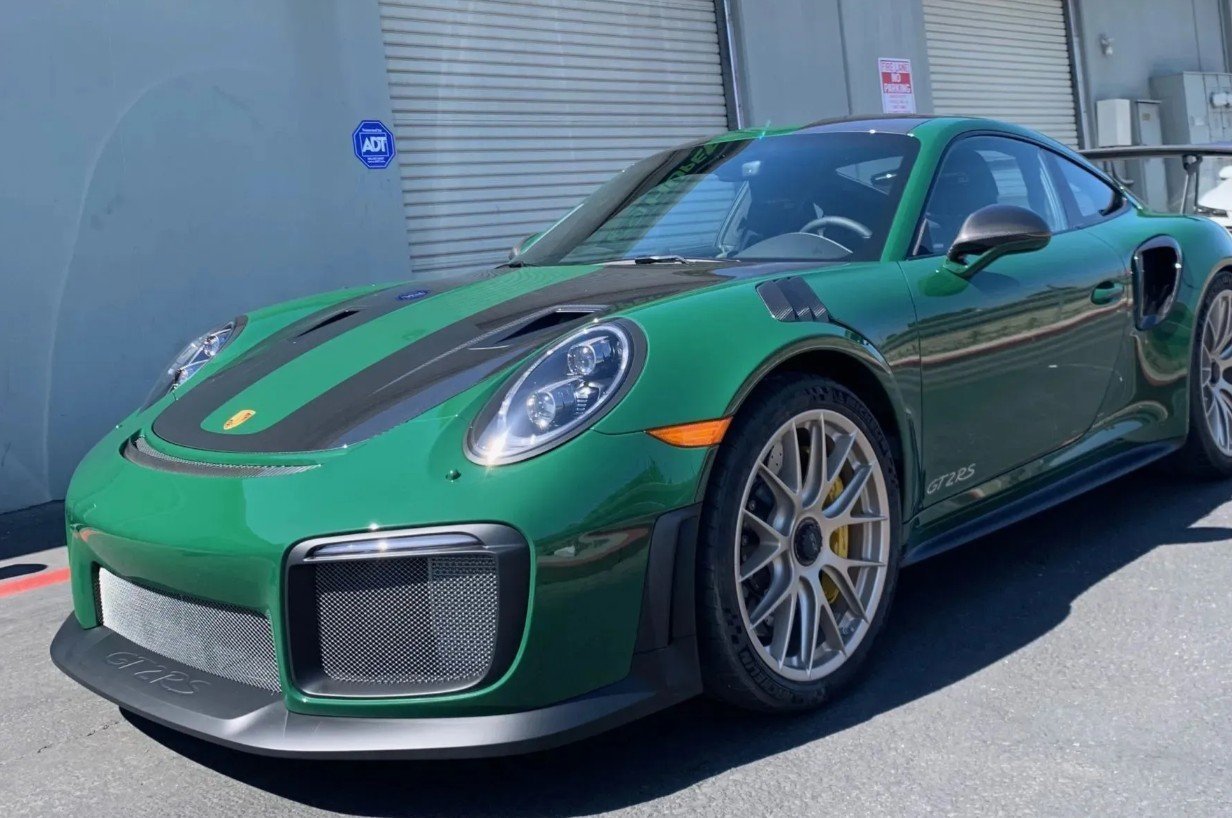 Green Porsche 911 GT2 sports car with black racing stripes parked in a lot