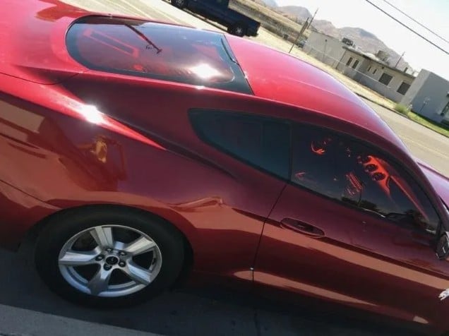 Red sedan car parked with customized dark tinted windows and silver alloy wheel visible on the side