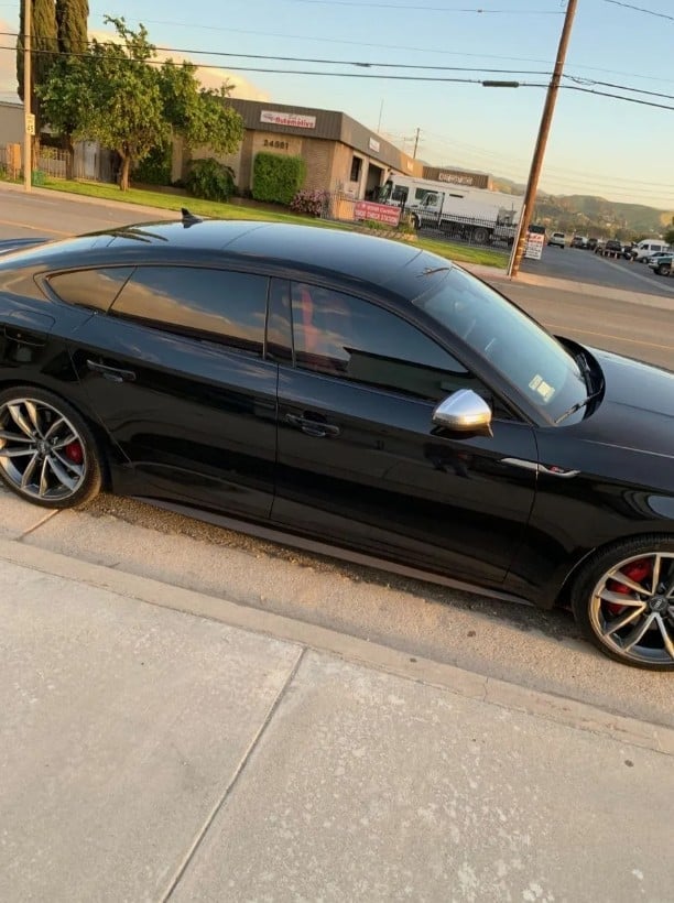 Black sports coupe parked on street with storefront and mountains in background