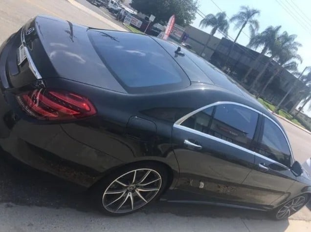 Black Mercedes-Benz sedan parked outdoors with palm trees visible in background