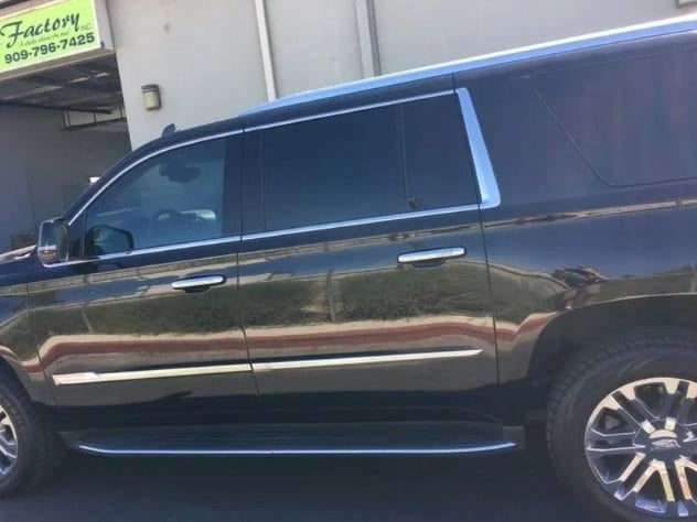 Side view of a black full-size SUV or minivan parked outside a garage building