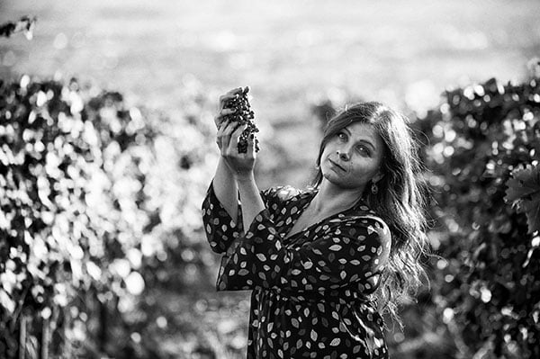 Woman in polka dot dress holding sunflower in field, black and white photo