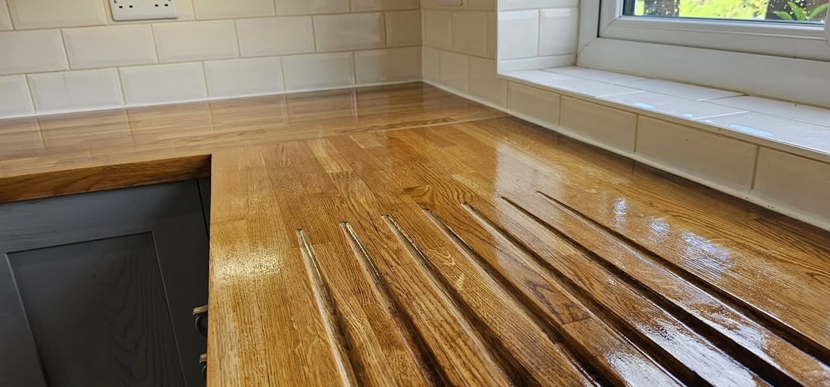 Wooden kitchen floor with brown hardwood planks and black cabinets visible on the left side