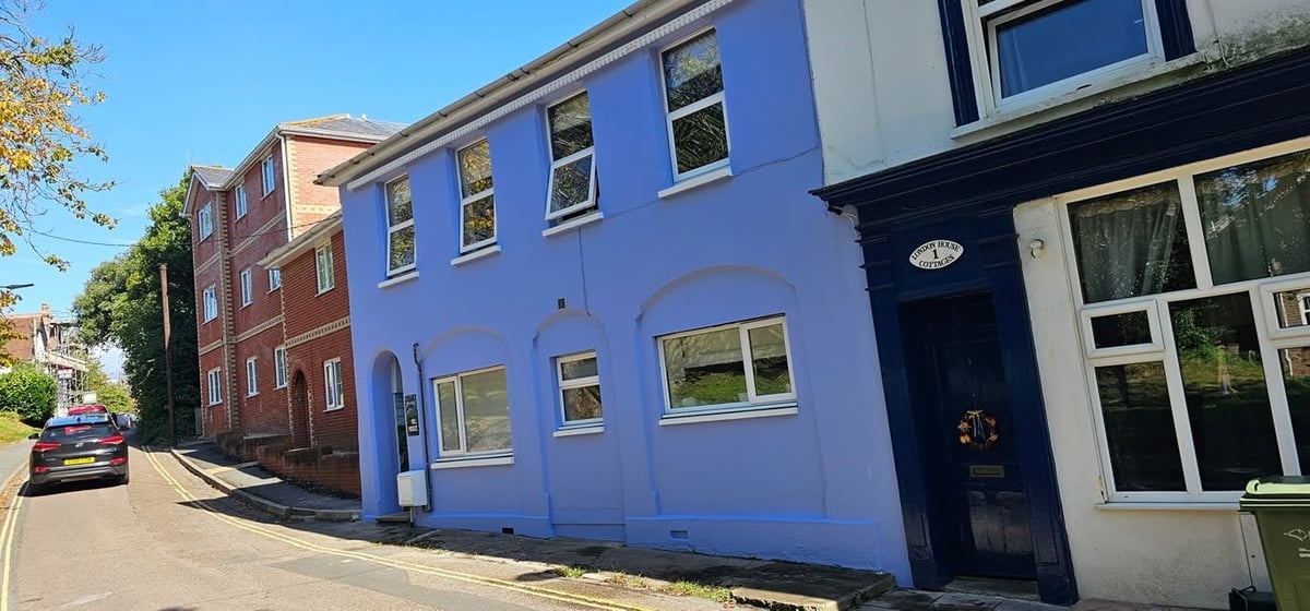 Row of colorful residential buildings including a bright blue painted house with multiple windows on a sunny residential street