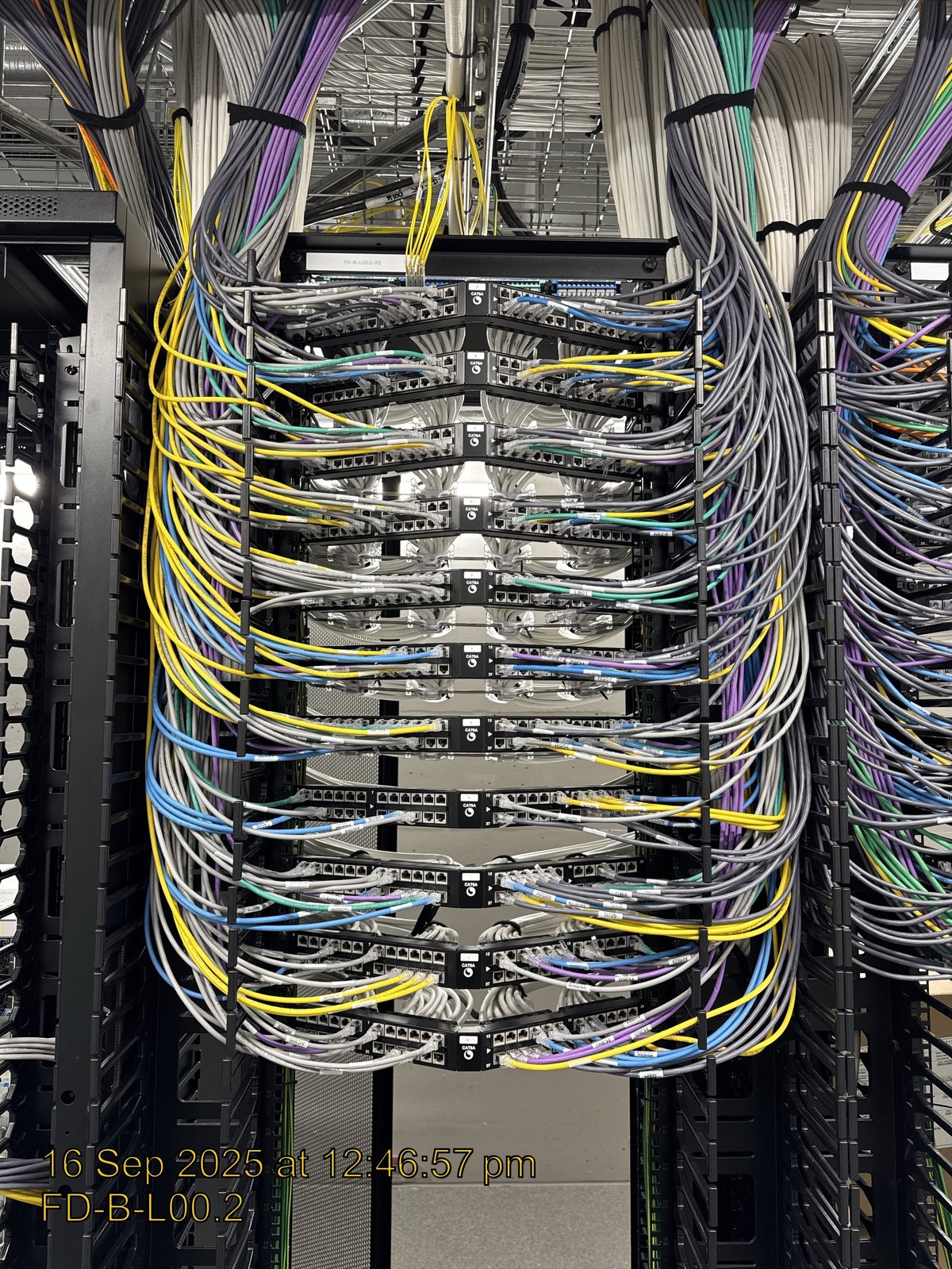 Network server rack with multiple colour-coded ethernet cables and network equipment stacked vertically