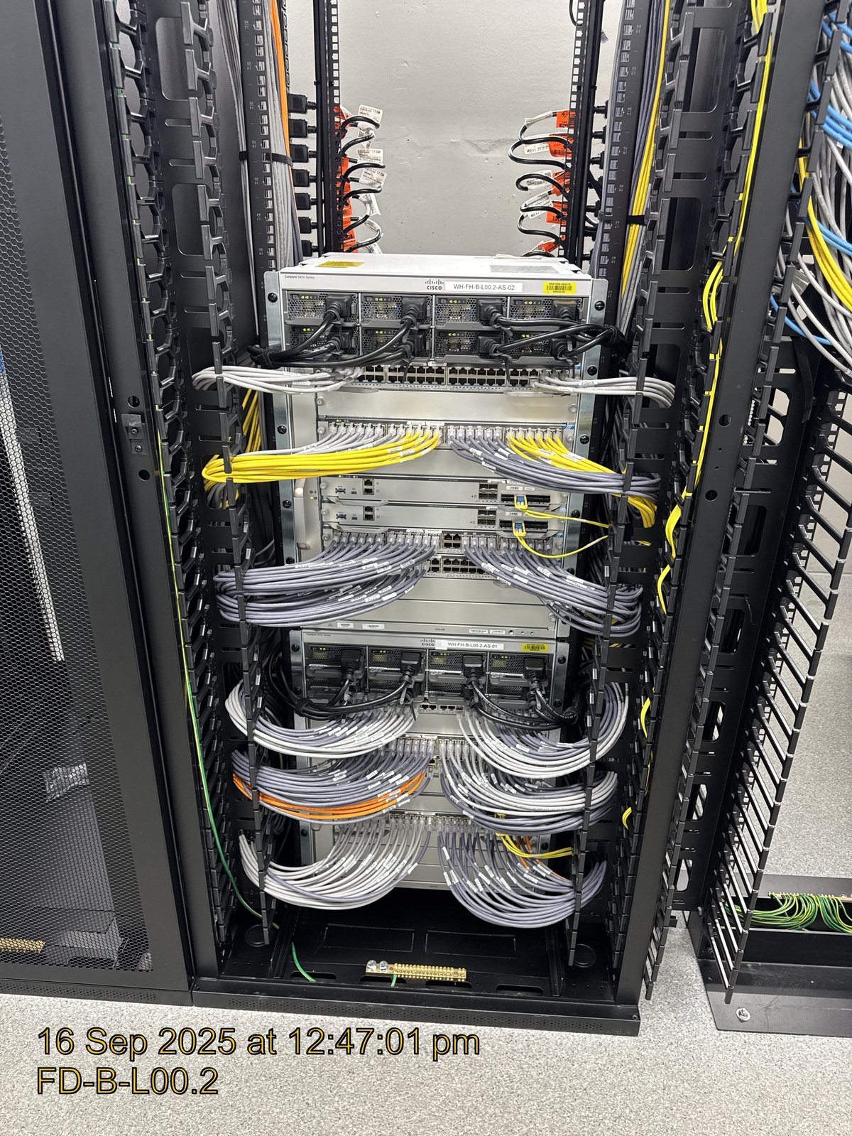 Server rack with organised network cables in yellow, white, and orange colours running through cable management trays