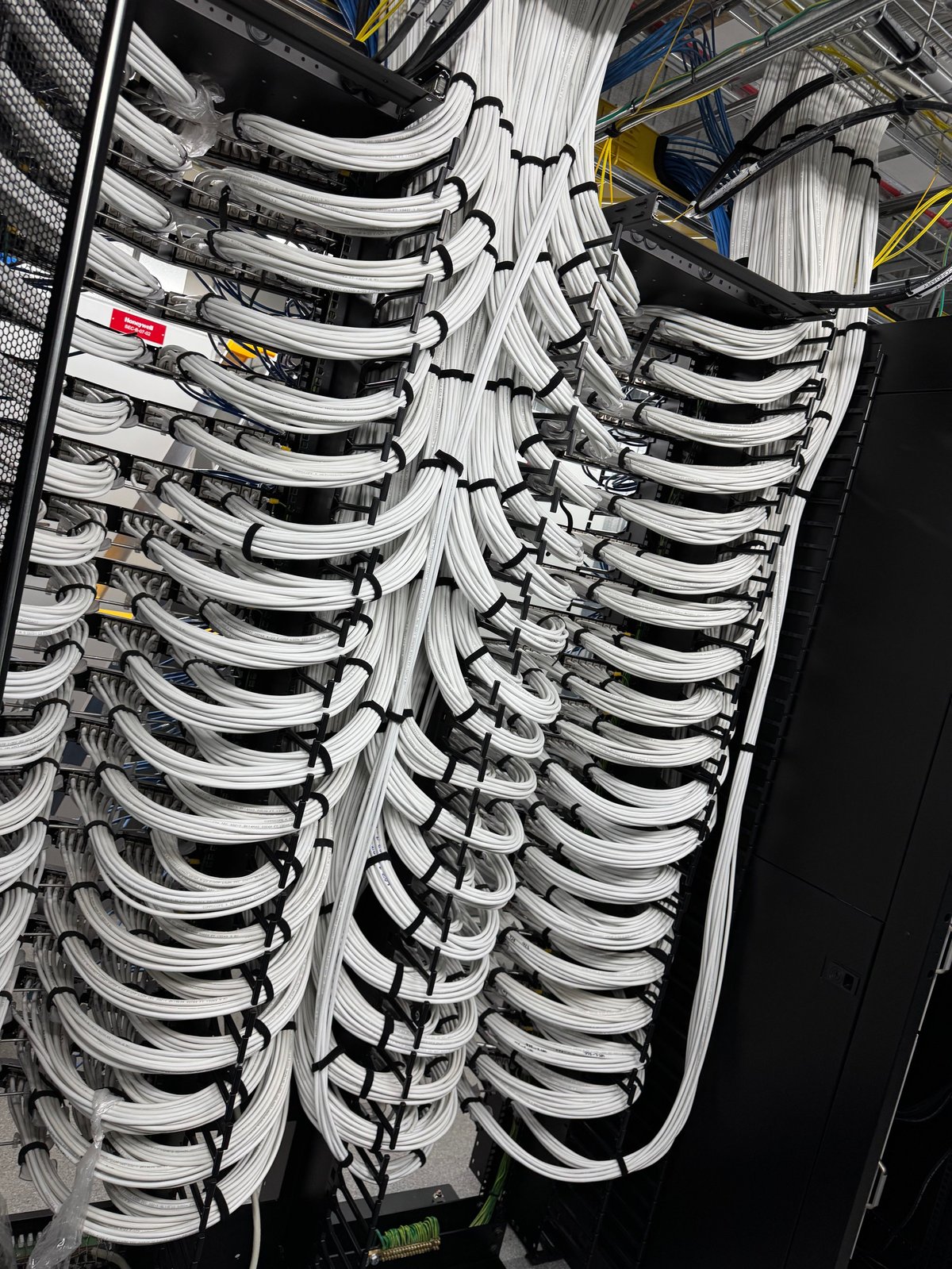 Overhead view of organised network cable management with white cables bundled in curved trays in a server rack.