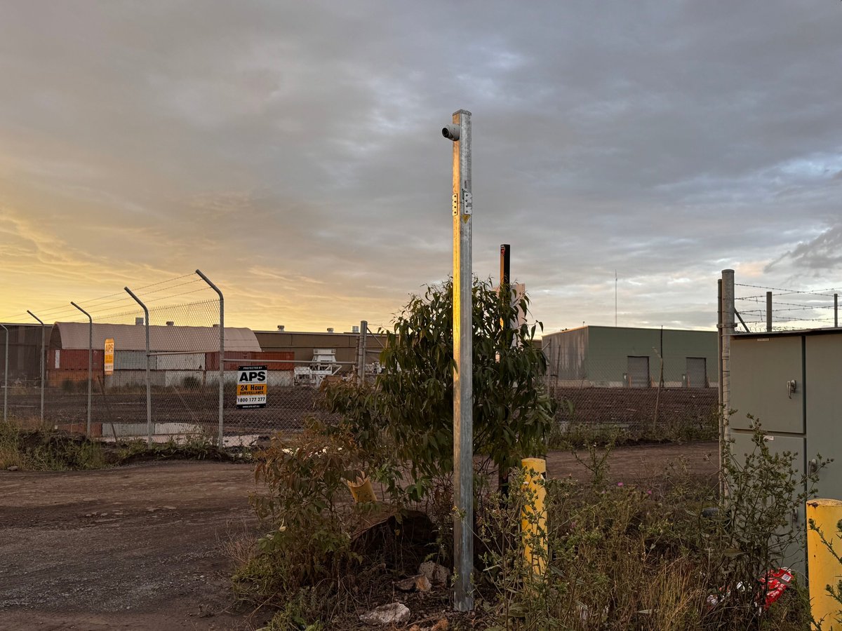 Industrial security installation at a Melbourne commercial site, showing communications poles and equipment installed at dusk