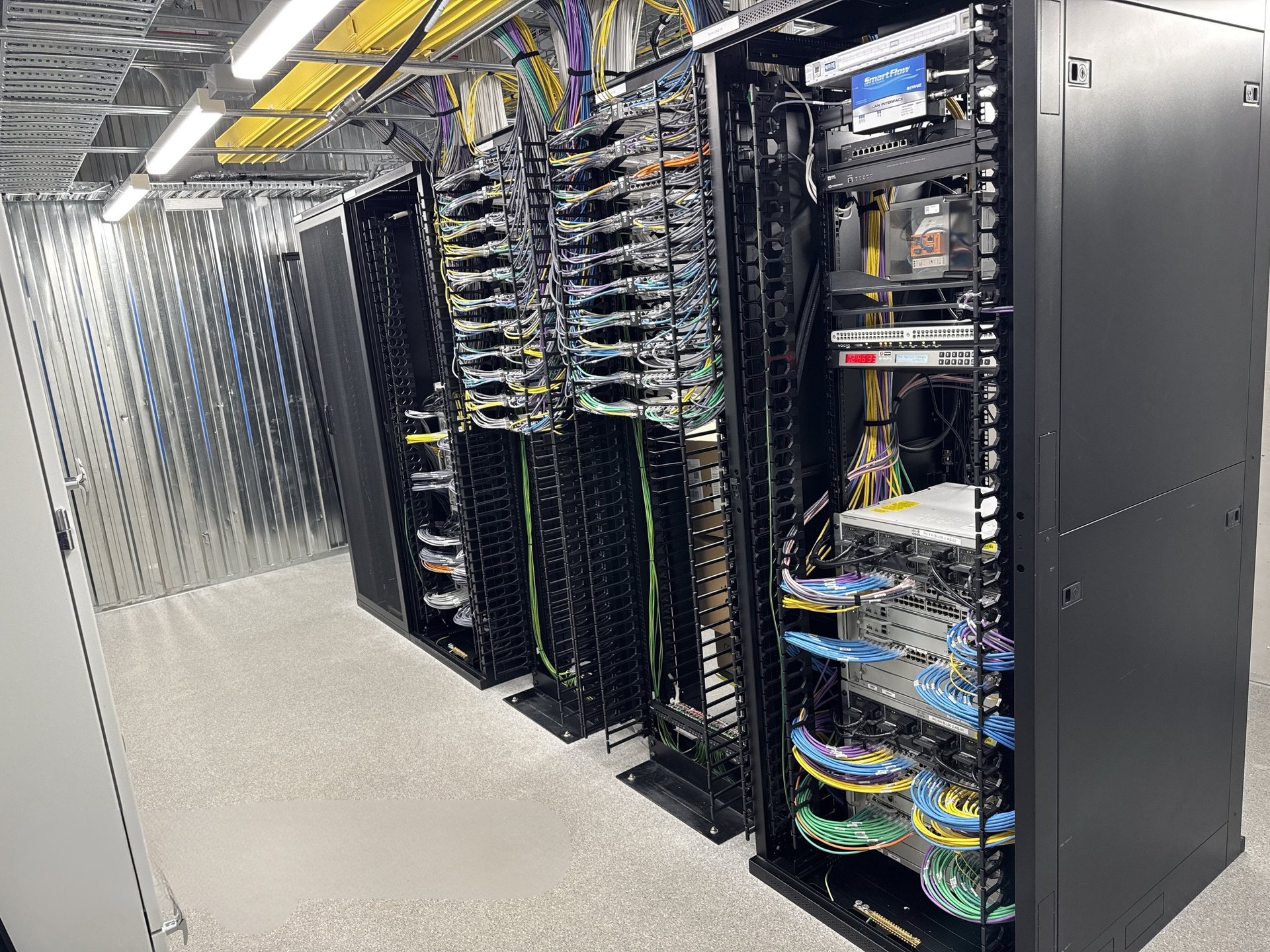 Data centre server racks with networking equipment, cables, and hardware in industrial facility