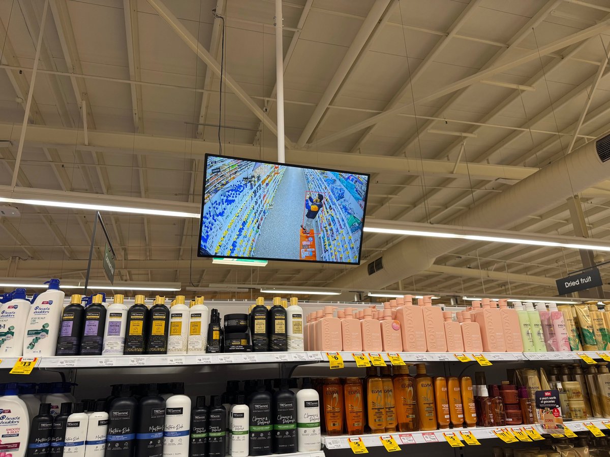 Commercial TV display screen mounted above retail shelving, installed for in-store advertising at a Melbourne shop