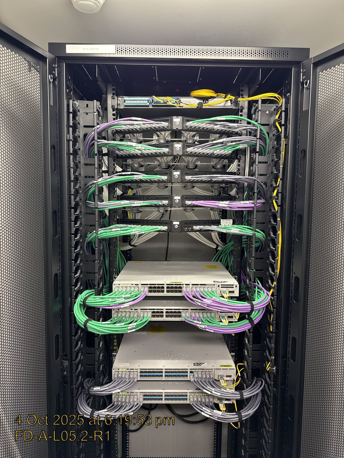 Server rack with network equipment and colour-coded cables organised in a data centre cabinet