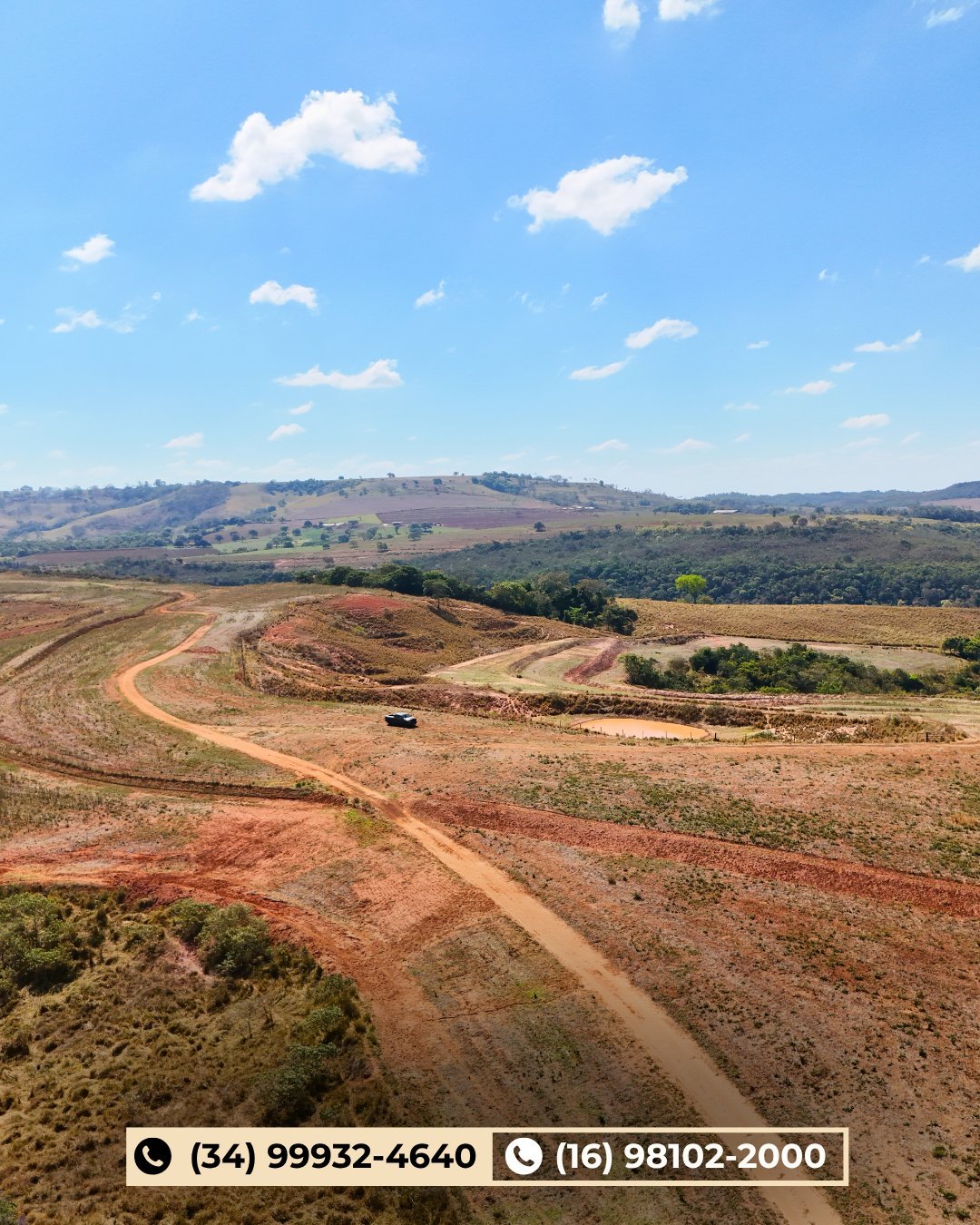 Vista aérea de terras agrícolas de solo vermelho com campos curvos arados, vegetação verde e céu com nuvens