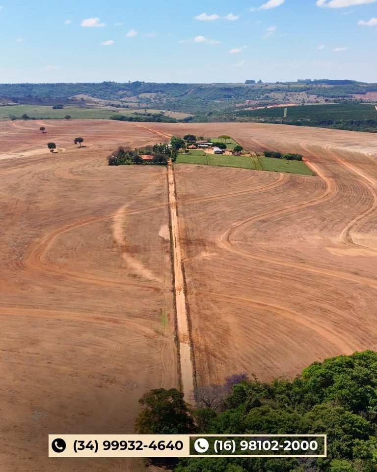 Vista aérea de propriedade rural cercada por vastos campos arados e estrada de terra de acesso