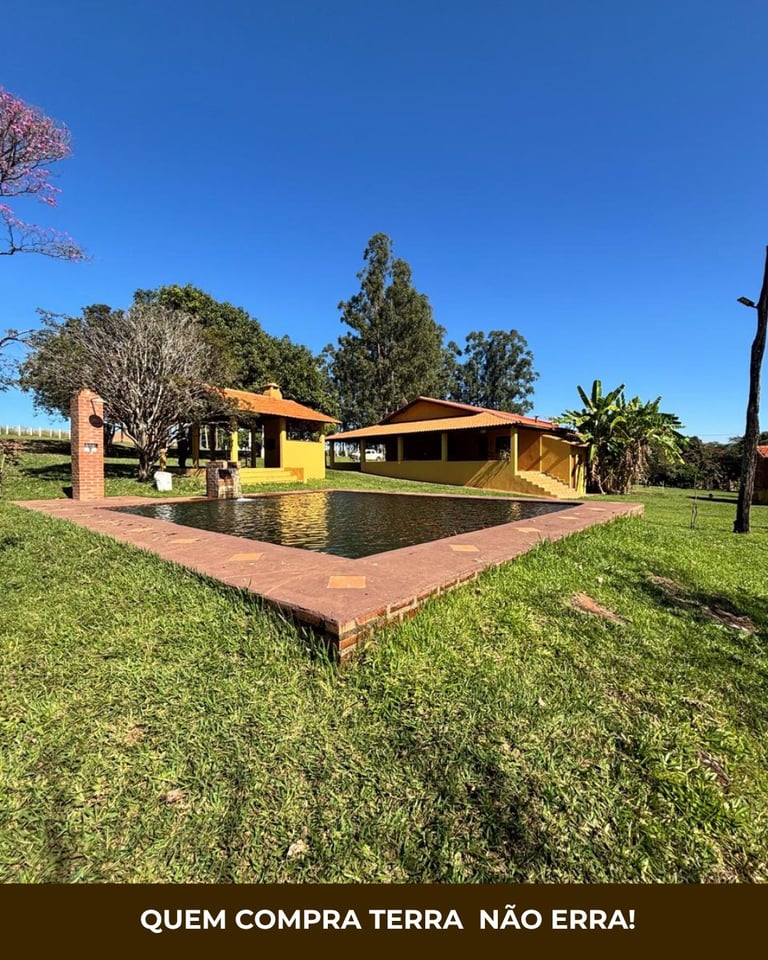 Sítio em Santa Cruz da Esperança com casa sede amarela, piscina, jardins e árvores ao redor