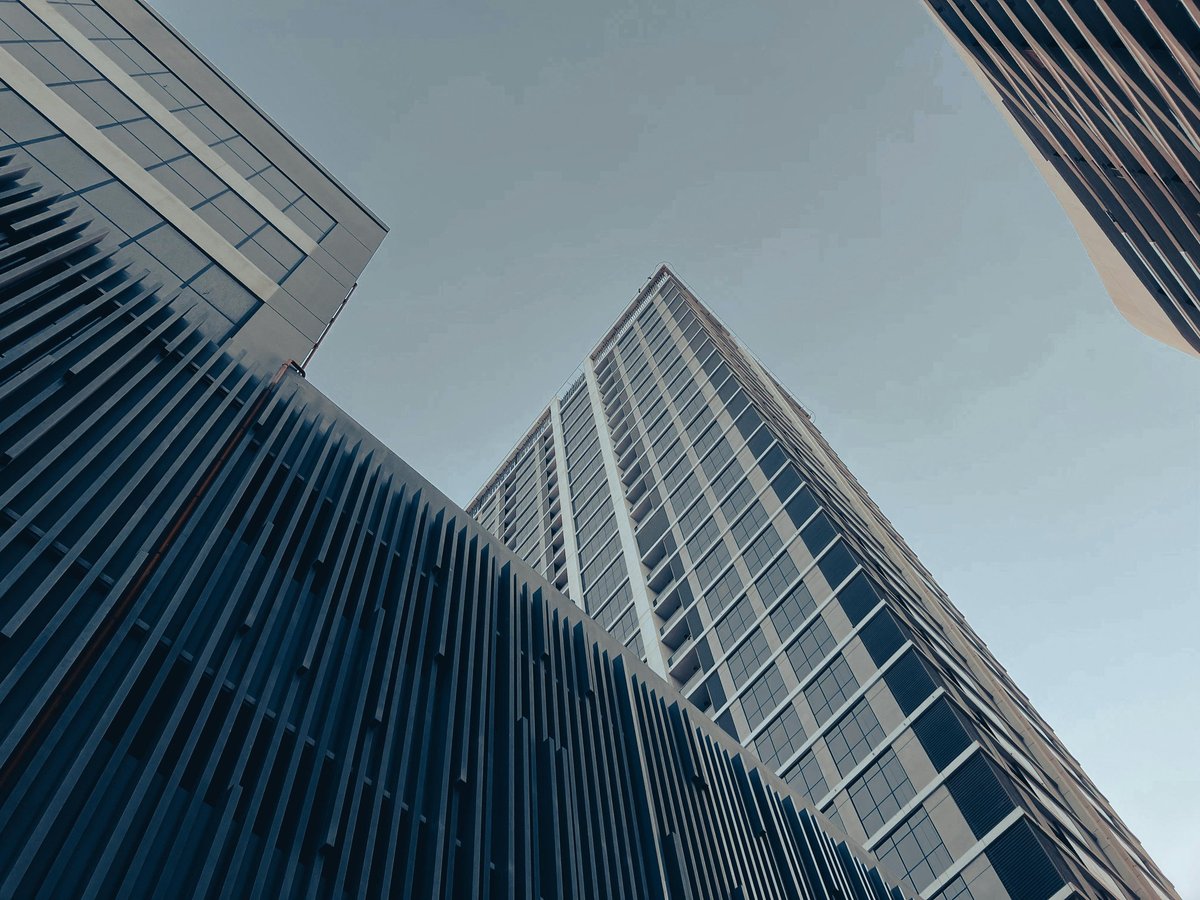 Low-angle view of modern glass and steel skyscrapers converging toward blue sky
