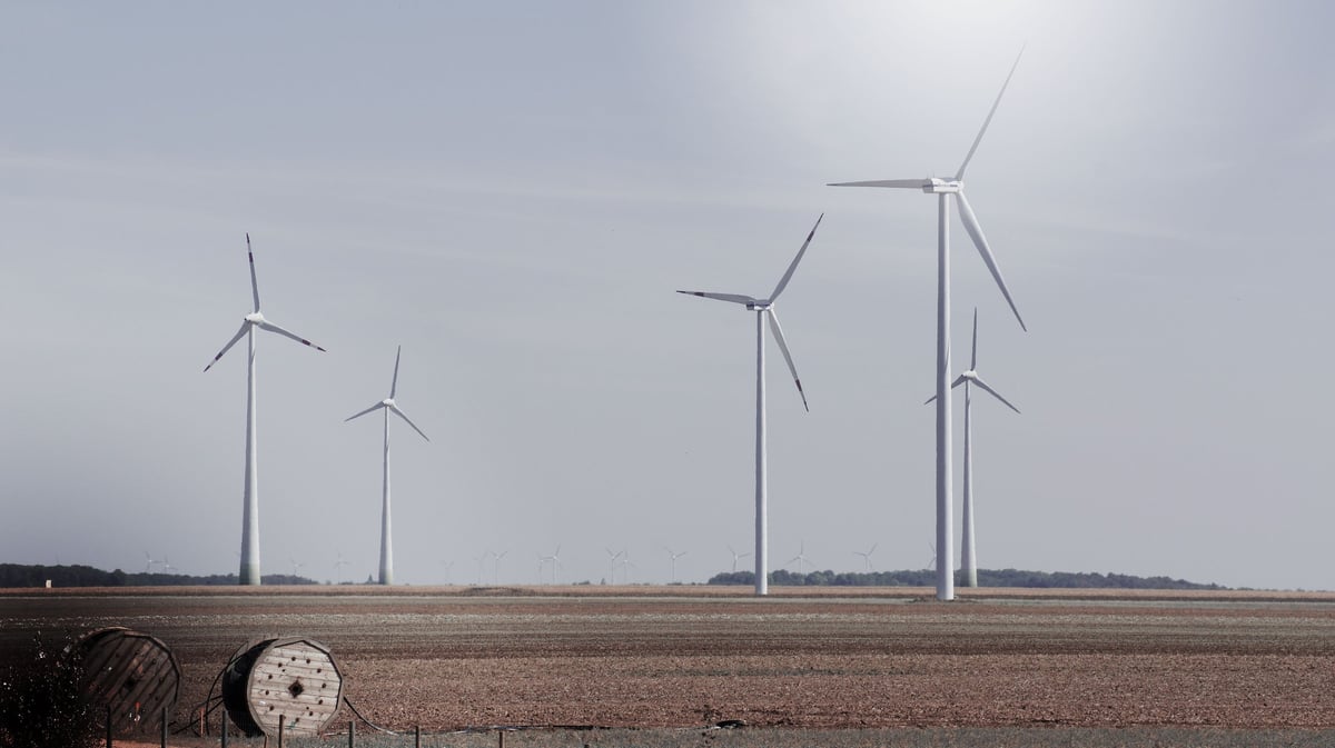 Wind turbines standing in a flat, open field under an overcast sky