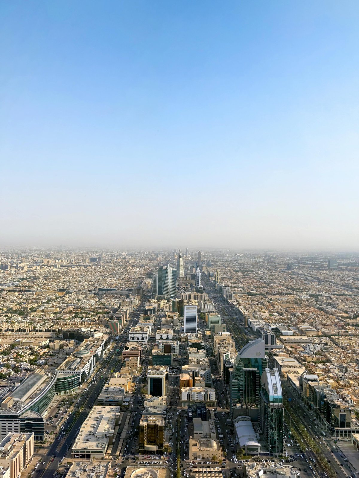 Aerial view of Riyadh skyline with modern skyscrapers and sprawling cityscape under clear blue sky