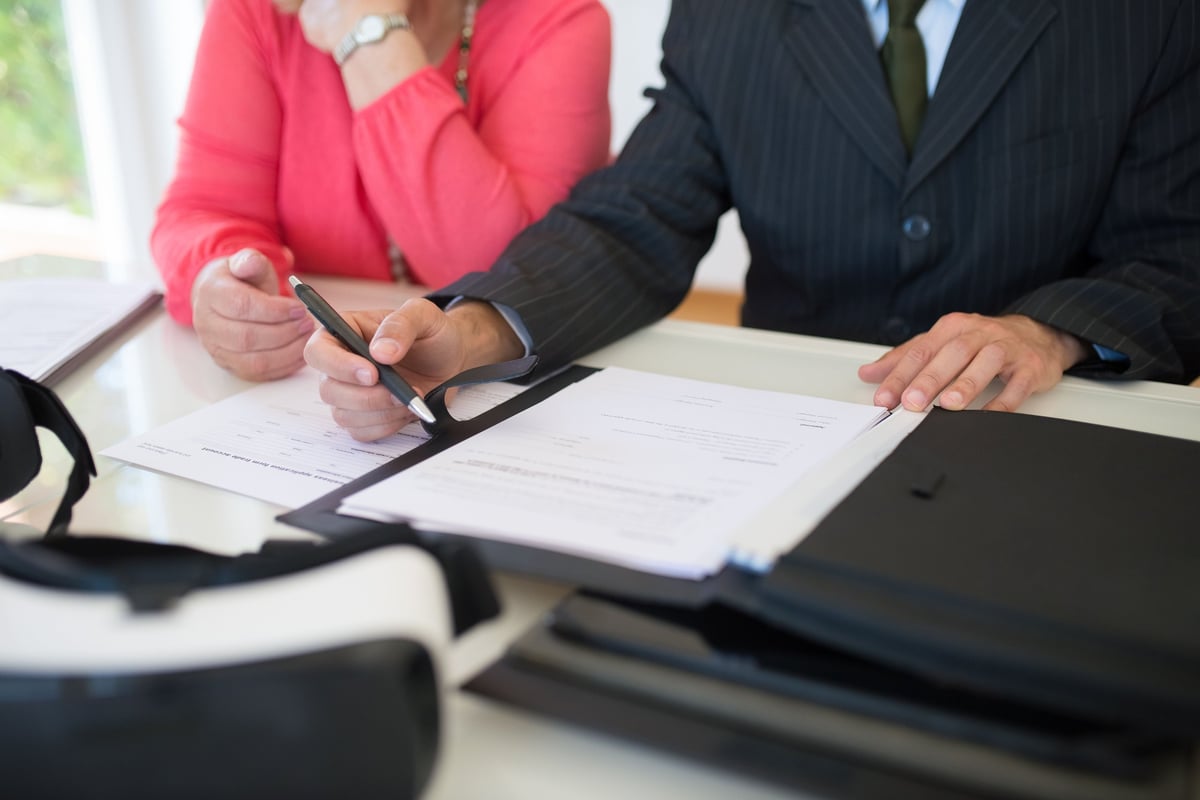 Two business professionals in formal attire reviewing documents together at a desk