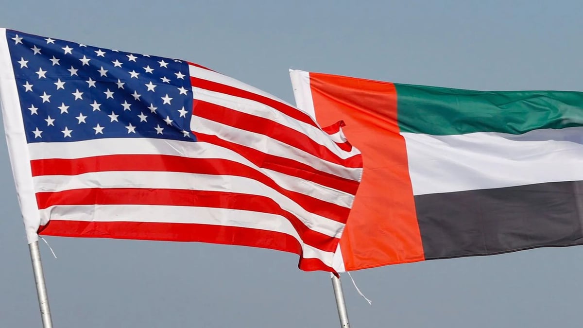 American flag and United Arab Emirates flag flying side by side against a blue sky
