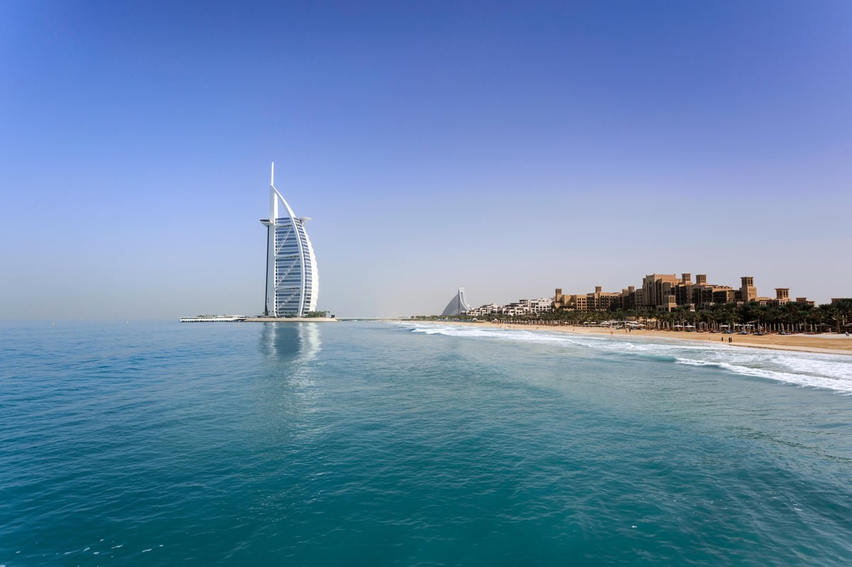Burj Al Arab luxury hotel on the beach in Dubai with turquoise waters and sandy coastline under clear blue sky