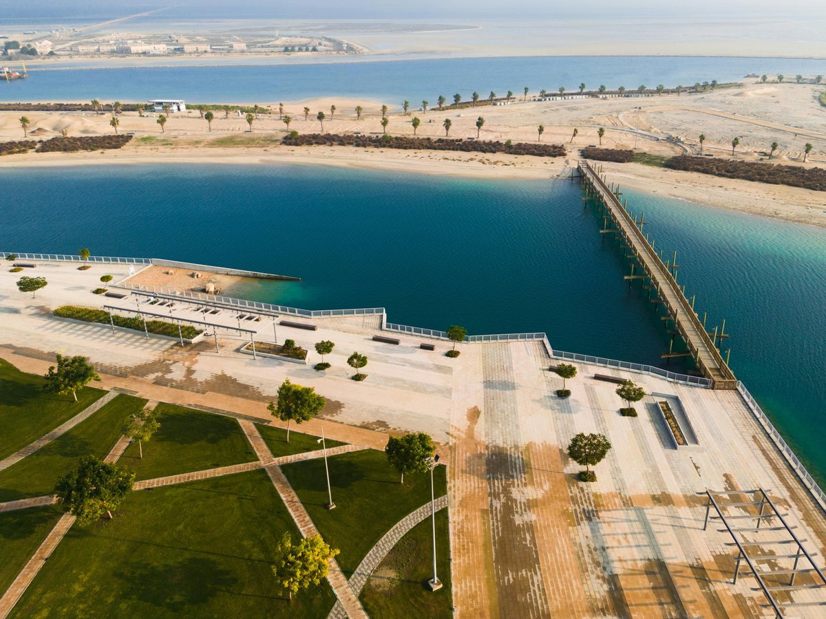 Aerial view of a modern waterfront development with turquoise lagoon, sandy beaches, green landscaping, and connecting bridges
