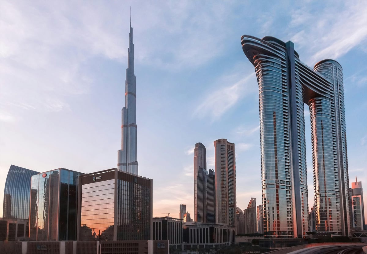 Dubai skyline at sunset featuring Burj Khalifa and modern skyscrapers against a blue cloudy sky
