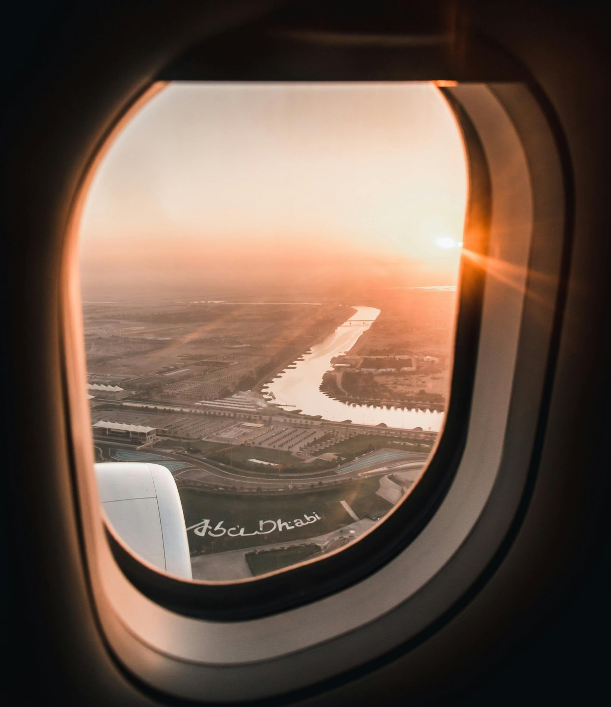 Airplane window view of a winding river and landscape at sunset over Abu Dhabi