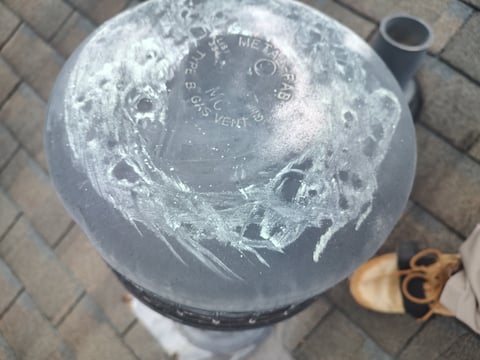 Overhead view of a clear plastic container with soapy water and foam residue, partially rinsed with a wooden brush visible beside it