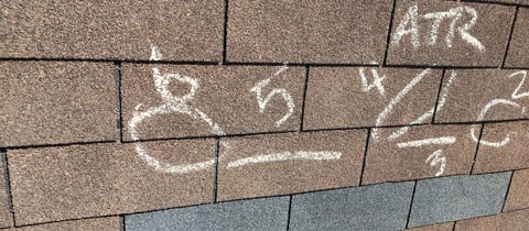 Chalk drawings and markings on brown brick or tile wall surface, including the letters ATR and various sketches