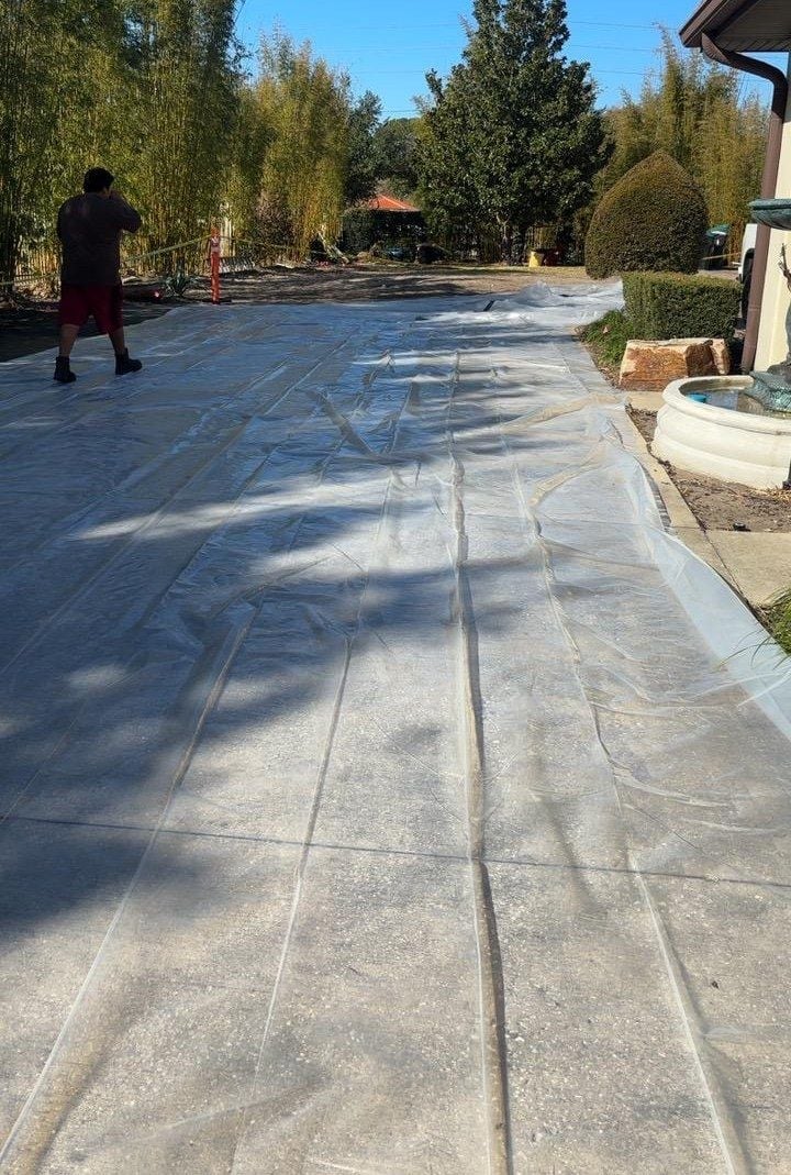 Long driveway covered with protective plastic sheeting ahead of a roof replacement